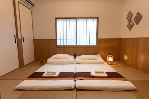 two beds in a large room with a window at Irodori Hotel AI in Fukuoka