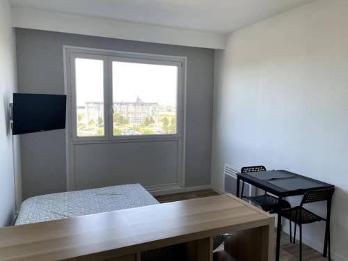 a room with a bed and a desk and a window at Studio Horizon Bleu, vue mer in Calais