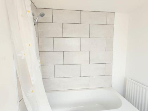 y baño con ducha de azulejos blancos y aseo. en Cozy Apartment en Cambois