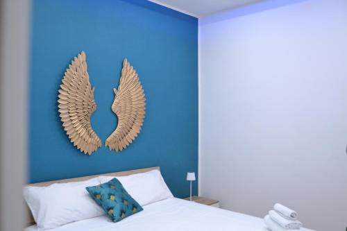 due ali d'oro su una parete blu sopra un letto di Anna's B&B a Pozzuoli