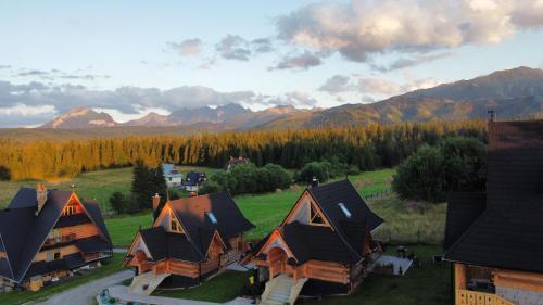 a group of cottages with mountains in the background at Bajkowa Osada Murzasichle domek z jacuzzi in Murzasichle