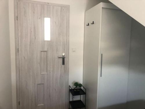 a wooden door in a white room with a window at Nowy tani apartament in Darłowo