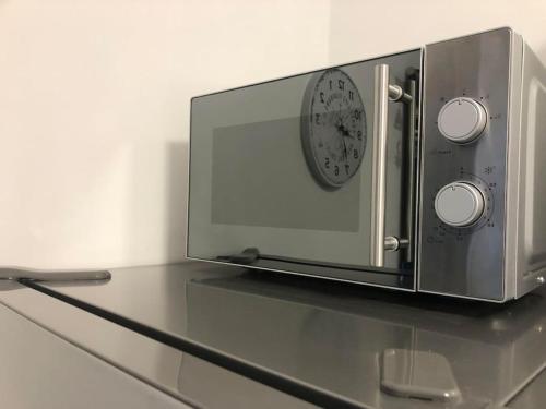 a microwave with a clock on top of a counter at Nowy tani apartament in Darłowo