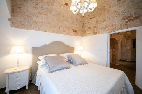 1 dormitorio con cama blanca y pared de ladrillo en Dimore nel Tempo - Widespread Homes & Trulli, en Alberobello