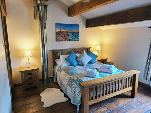a bedroom with a bed with blue pillows at The Shippon Barn with Hot Tub and Private Pool in Wirral