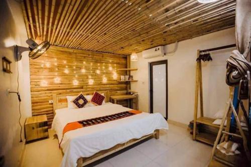 1 dormitorio con 1 cama grande y pared de madera en Indigo Inn Sapa, en Sa Pa