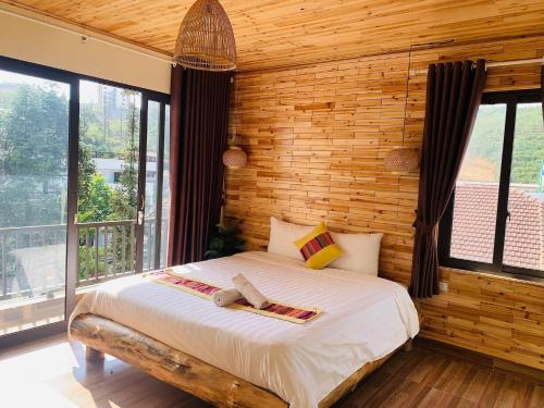 1 dormitorio con 1 cama con paredes y ventanas de madera en Indigo Inn Sapa, en Sa Pa