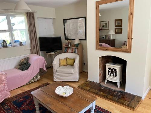 a living room with a table and a fireplace at Snipe Vineyard Cottage in Woodbridge