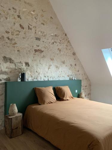 une chambre avec un grand lit avec une tête de lit verte dans l'établissement Cottage au cœur du Perche, à Souancé-au-Perche