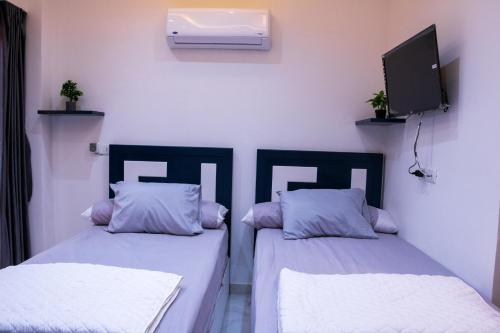 2 camas en una habitación con TV en la pared en ستديو مفروش - غرفة فندقيه - للايجار Studios - Room, en Seis de Octubre