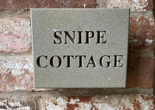 a sign on a brick wall that reads singateate at Snipe Vineyard Cottage in Woodbridge