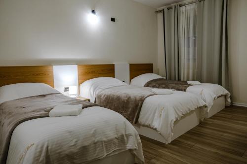 a hotel room with three beds with white blankets at Vila Pllaha in Korçë