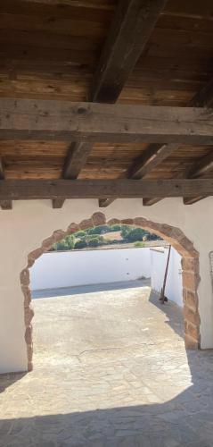 a stone archway in a building with a wooden ceiling at Villa Nuragica Sardegna in Bacu Abis