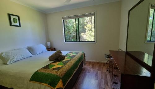 a bedroom with a bed and a dresser and two windows at Bellthorpe Stays in Maleny