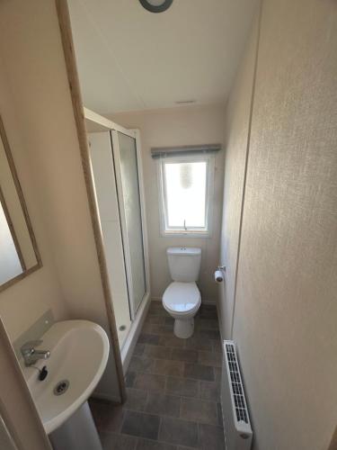 a small bathroom with a toilet and a sink at Butlins Skegness Caravan in Lincolnshire