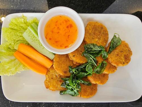 a plate of food with a bowl of dipping sauce and vegetables at Nimith Hotel & Restaurant in Phnom Penh
