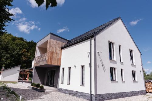una casa blanca con techo negro en Cabana 1407 Valea Avrigului, en Avrig