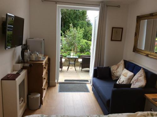 sala de estar con sofá azul y puerta corredera de cristal en Hardy Croft Hideaway, en Grassington