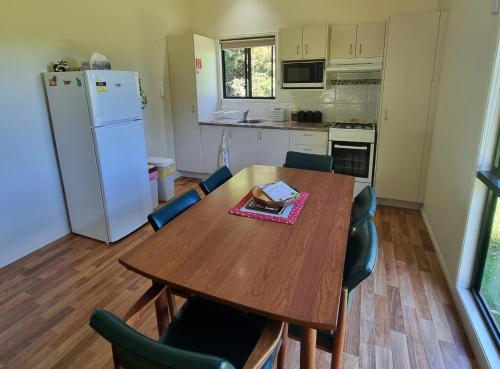 a kitchen with a table and chairs and a refrigerator at Bellthorpe Stays in Maleny