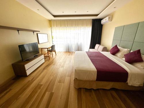 a hotel room with a bed and a flat screen tv at villa Mojito in Koh Samui