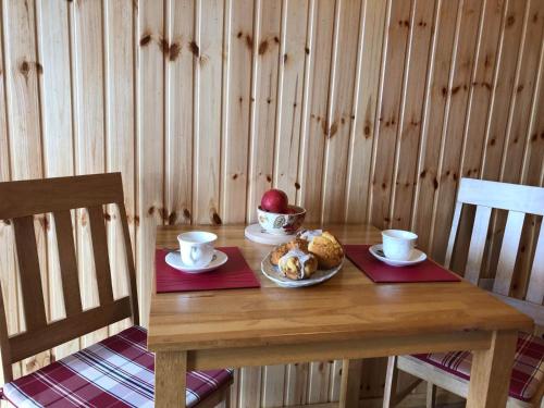 a wooden table with a plate of food and two cups at Neadín Beag in Tralee