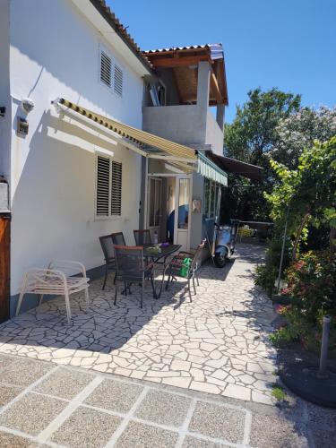 a patio with chairs and a table in front of a house at APP Leo in Rab