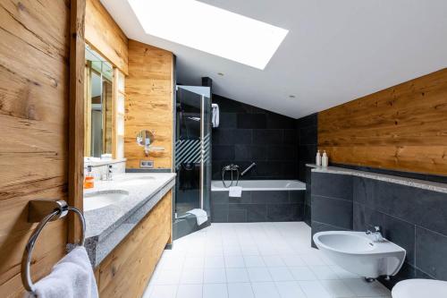 a bathroom with a sink and a toilet and a tub at Seehotel Schlierseer Hof in Schliersee
