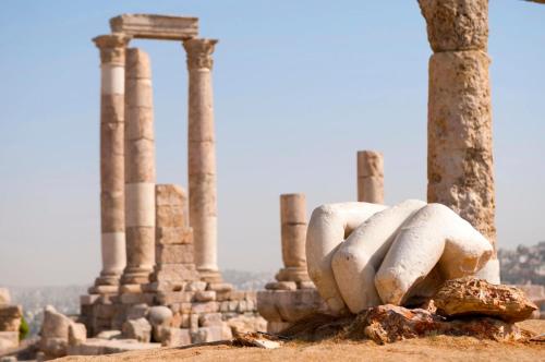 a stone statue in front of the ruins of a building at City Citadel Hotel,Amman in Amman
