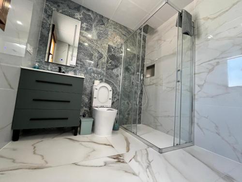 uma casa de banho com um WC e uma cabina de duche em vidro. em Calpe apartamento lujoso bajo terasa piscina aire cerca playa pueblo em Calpe