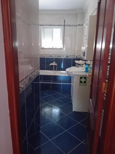 uma casa de banho azul com um lavatório e uma banheira em PESO RIVER HOUSE em Melgaço