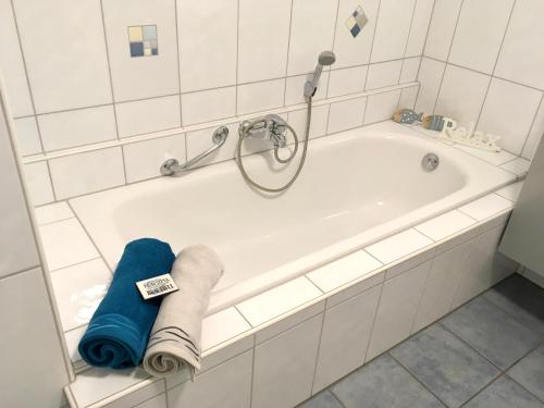 eine weiße Badewanne mit blauem Handtuch darauf in der Unterkunft Schöne Gartenwohnung im Seenland in Wackersdorf