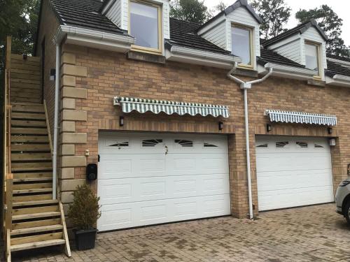 a house with two garage doors and a staircase at Luxury Studio Loft with Car Charging Point in Frizington