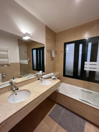 baño con 2 lavabos, bañera y espejo grande en Quite & relaxing private apartment for 2-6 pers - Golf & Pool resort - Murcia, en Murcia
