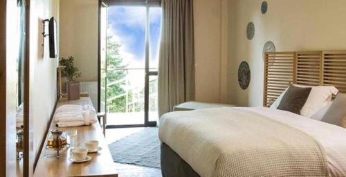 a bedroom with a large bed and a large window at Natura Hotel Vytina in Vytina