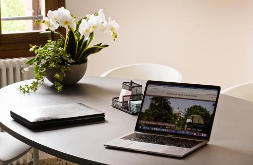 a laptop computer sitting on a table with a vase of flowers at Maison Boutique Al Redentore in Venice