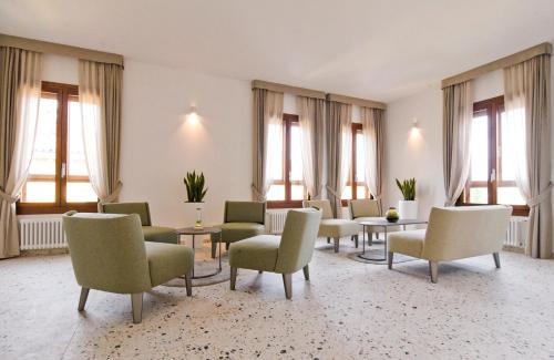 a waiting room with chairs and tables and windows at Maison Boutique Al Redentore in Venice