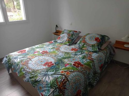 Cama con edredón y almohadas coloridos en Maison neuve au calme avec jardin, en Gaillan-en-Médoc