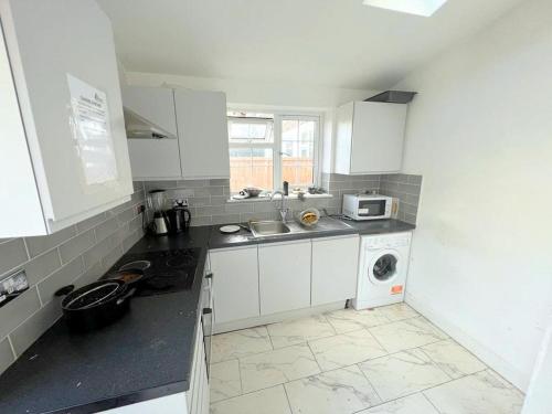a kitchen with a sink and a washing machine at Lilleshall Rooms in Mitcham