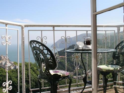 Un balcón con sillas y una mesa con vistas. en Highcliffe House, en Lynton