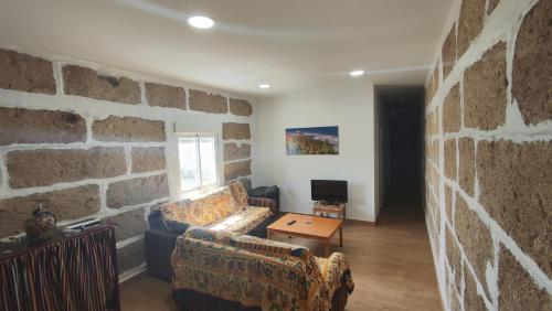 アロナにあるLA CASA DEL ALMÁCIGOの石壁のリビングルーム(ソファ2台付)