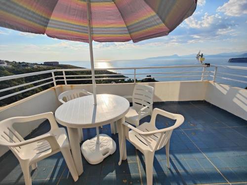 einen Tisch und Stühle auf einem Balkon mit Sonnenschirm in der Unterkunft Appartamento La Perla in San Nicola Arcella