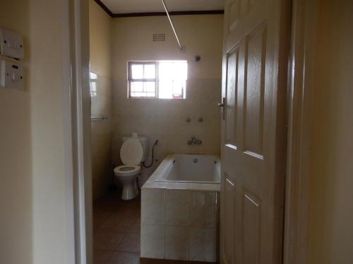 a bathroom with a tub and a toilet and a window at Quest in Lilongwe