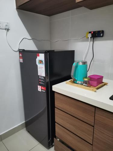 a kitchen with a black refrigerator and a counter at Ilsham Guest House @ Seroja Hills BBST Sepang in Sepang