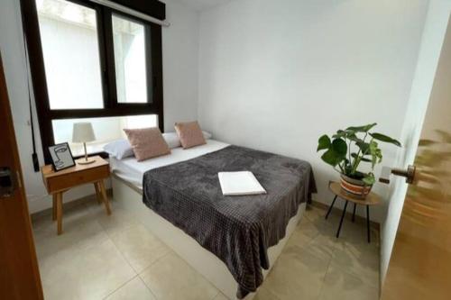 Un dormitorio con una cama y una mesa y ventanas. en Taima Flats 3, en Alicante