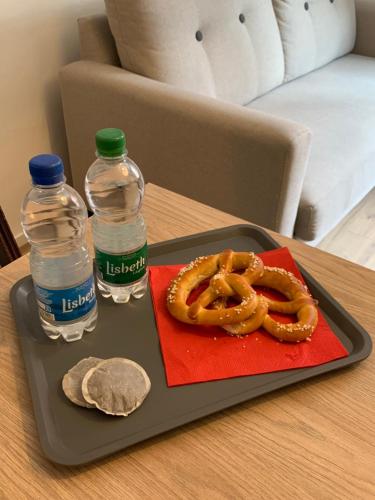 a tray with a pretzel and two bottles of water at Gîte du clocher dans ancienne maison du vignoble in Niedermorschwihr