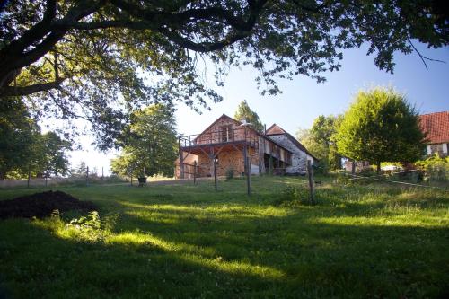 une maison sur un champ herbeux avec un arbre dans l'établissement Gite Fleurs d'Esse, à Saint-Paul-la-Roche