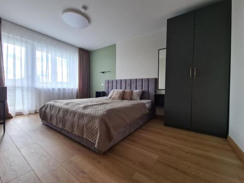 a bedroom with a bed and a large window at Samanų apartamentai in Šiauliai