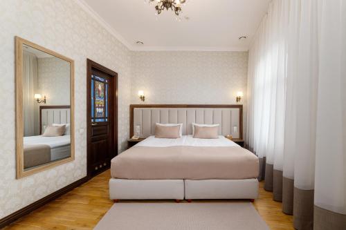 ein Schlafzimmer mit einem großen Bett und einem Spiegel in der Unterkunft Feder Boutique Hotel in Lwiw