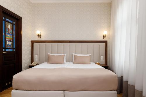 1 dormitorio con 1 cama blanca grande y 2 almohadas en Feder Boutique Hotel, en Leópolis