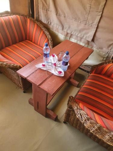 a wooden table with two bottles of water and two chairs at Masai Mara Explore Camp in Narok